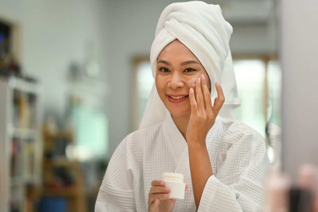 Smiling Beautiful Woman With Towel On Head Applying Nourishing C