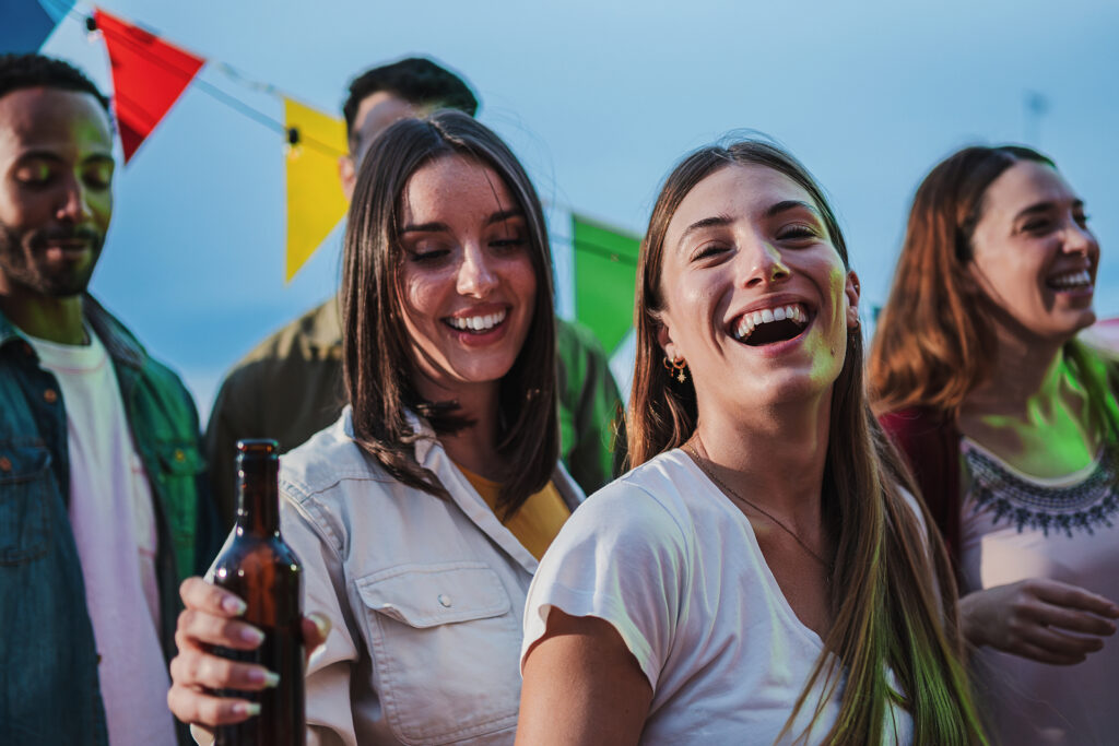 Two Young Women Dancing And Having Fun With A Happy Group Of Bes